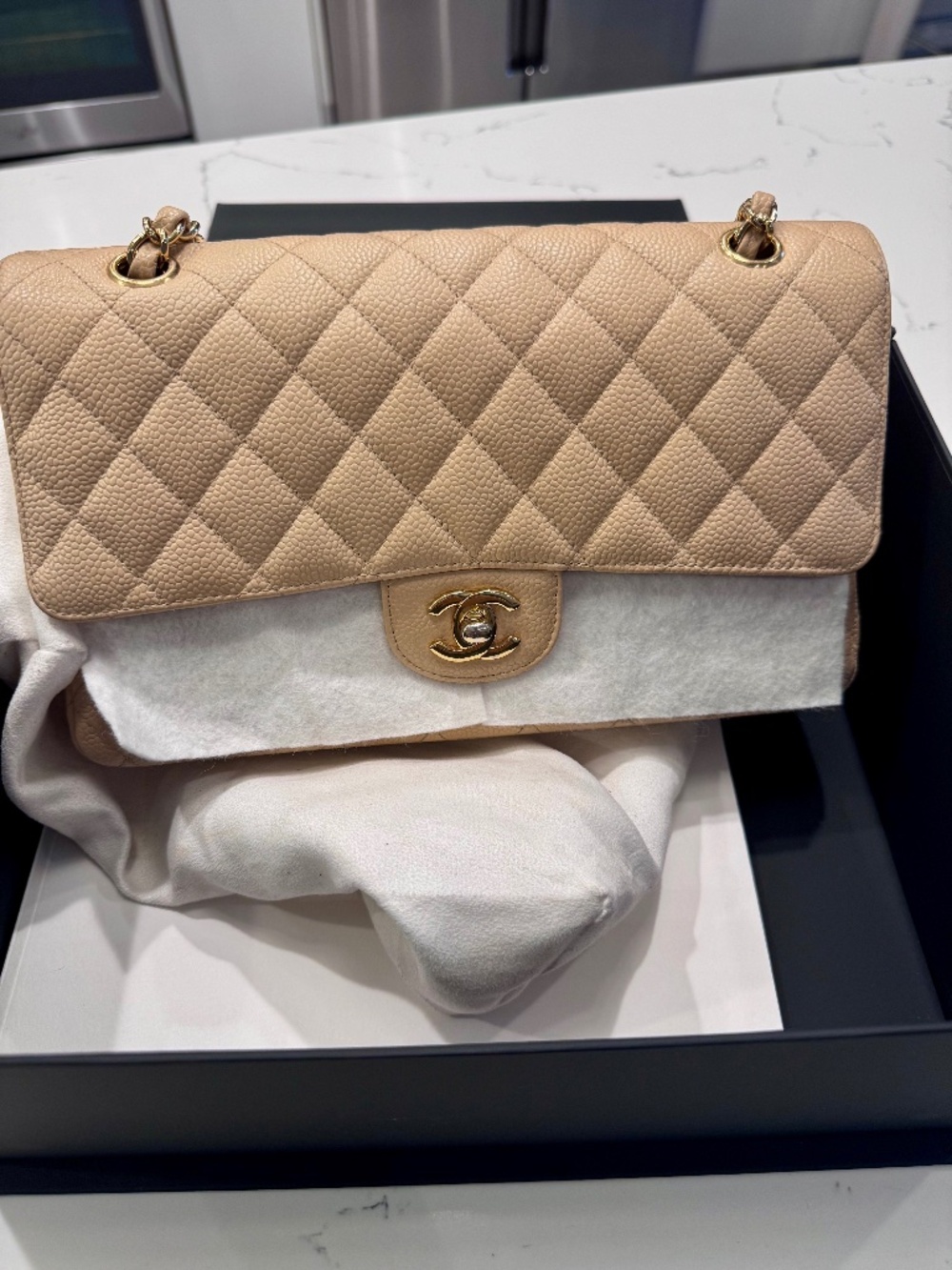 Chanel Classic Medium Double Flap in beige nude caviar with gold tone hardware.